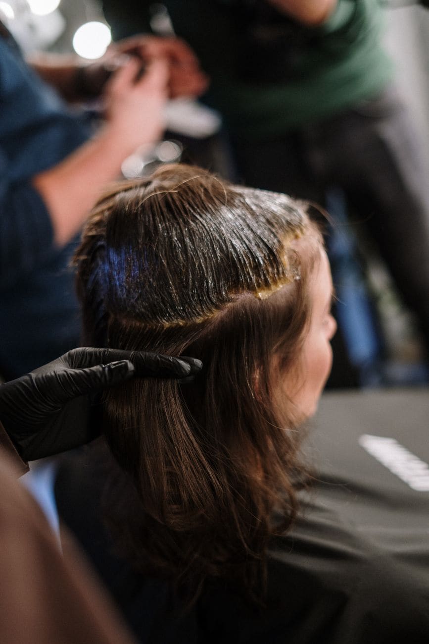 Kaderníčka farbí vlasy klientke v salóne Aura Cabello